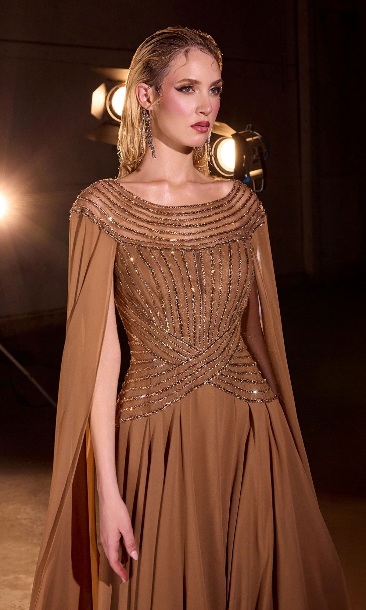 A woman in the Cape-Sleeve Long Bronze Formal Dress: Ladivine CL08 stands before studio lights, gazing to the side.